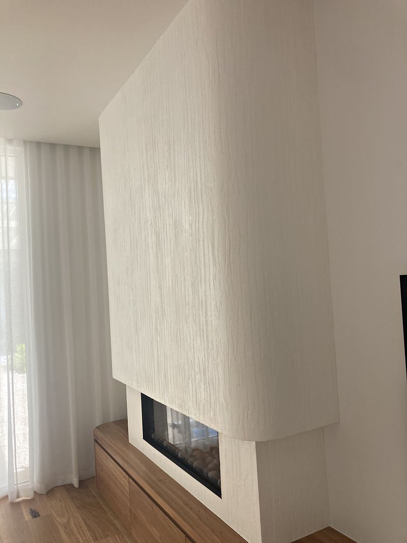 The curved white fireplace seen from the side, showing the full feature wall and the fire below